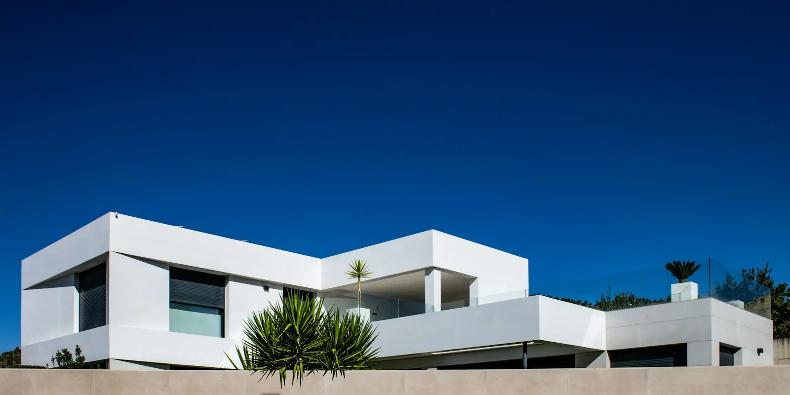 Vivienda unifamiliar contemporánea de volúmenes blancos bajo un cielo azul intenso
