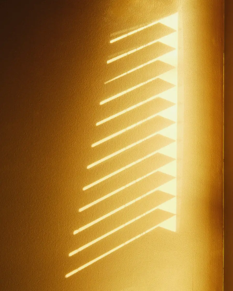 Luz cálida del atardecer filtrándose entre las lamas de una persiana
