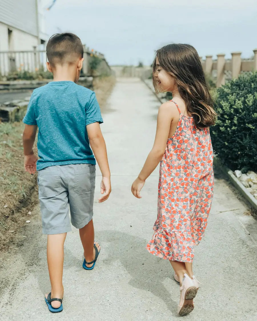 Dos niños caminando juntos por un camino de vuelta a casa