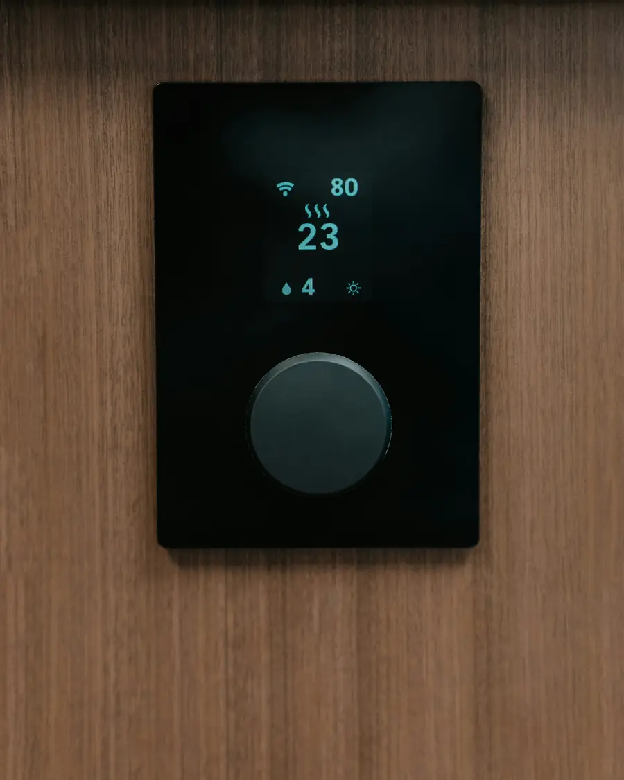 Termostato inteligente negro con pantalla integrado en un panel de madera